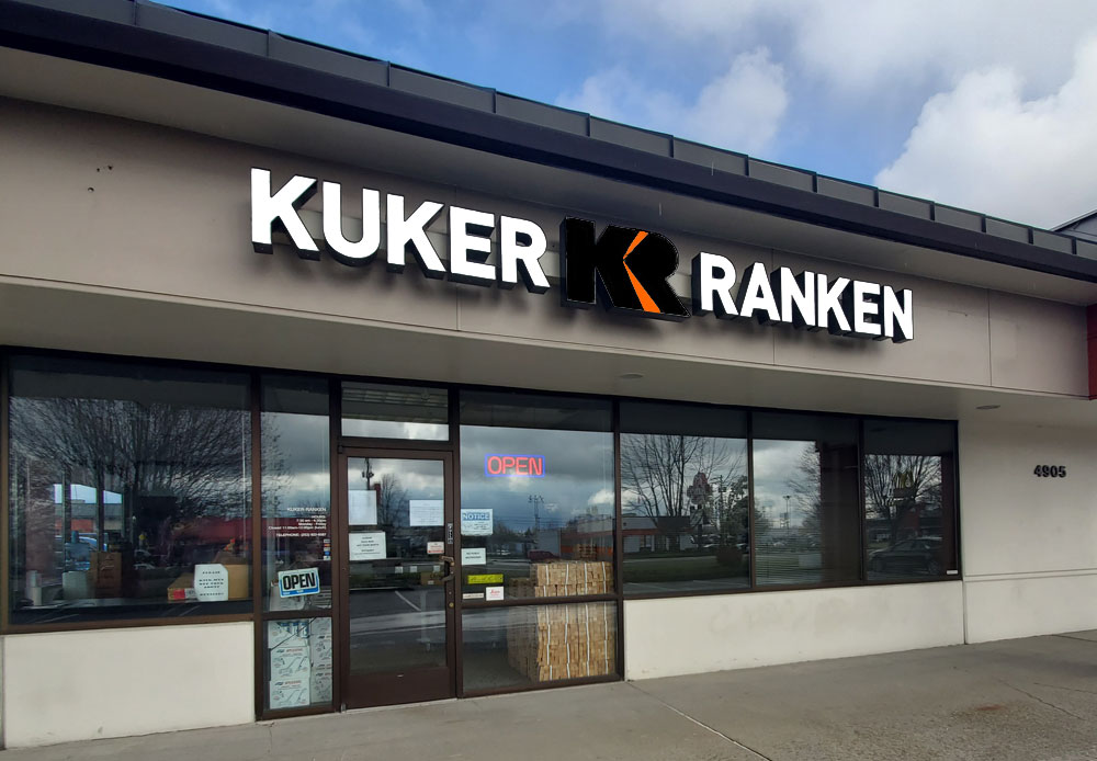 A building with a glass entrance with a neon board and Kuker-Ranken written on top