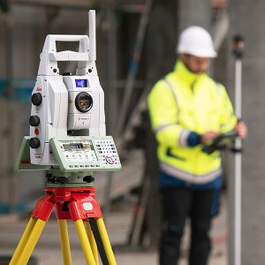 A construction worker is standing next to a Leica MS60 Nova MultiStation.