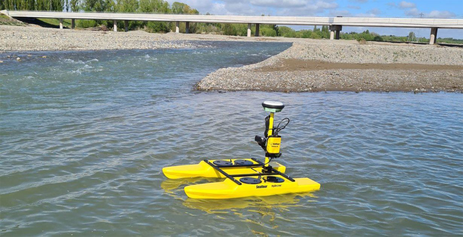 Yellow hydrographic survey boat on river.