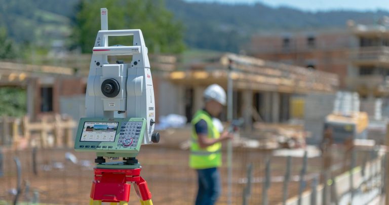 A construction worker is standing next to a surveying machine.