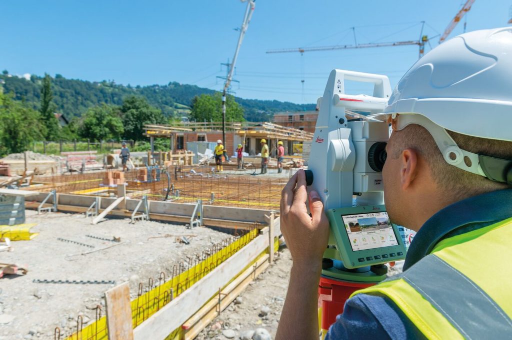 A construction worker using a surveyor's instrument on a construction site.