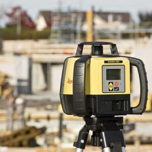 A construction site with a Leica Rugby 680 Rotating Laser on a tripod.