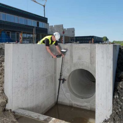 Worker measuring concrete structure on construction site.