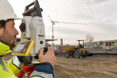 Surveyor using equipment at construction site.