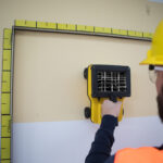 Worker using wall scanner for inspection.