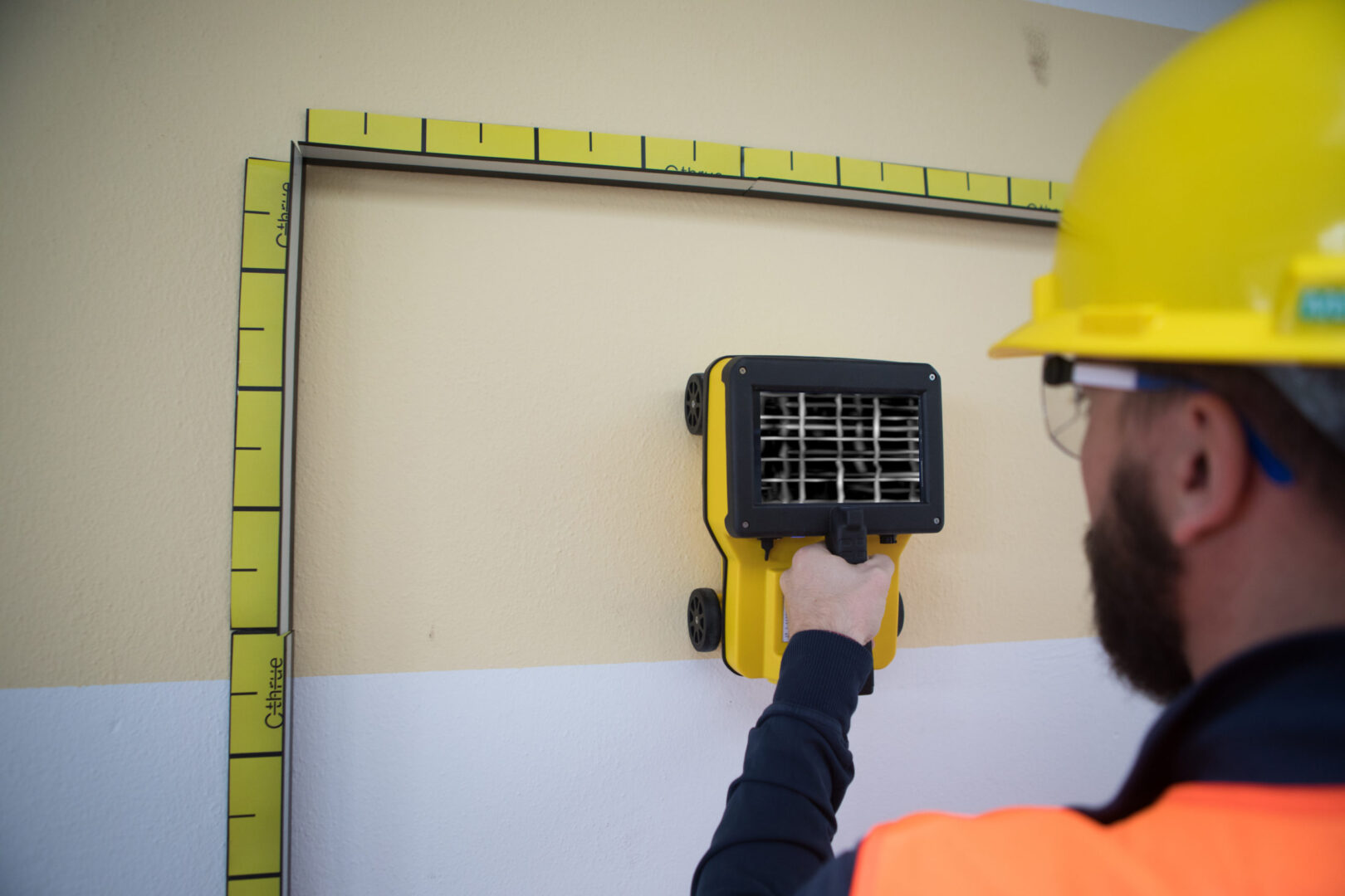 Worker using wall scanner for inspection.