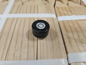 Black circular level on wood planks.