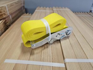 Yellow ratchet strap on wooden planks.