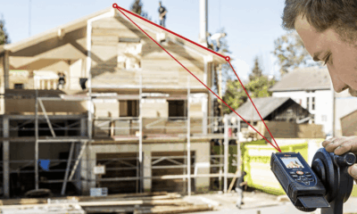 Construction worker using measurement tool outdoors.