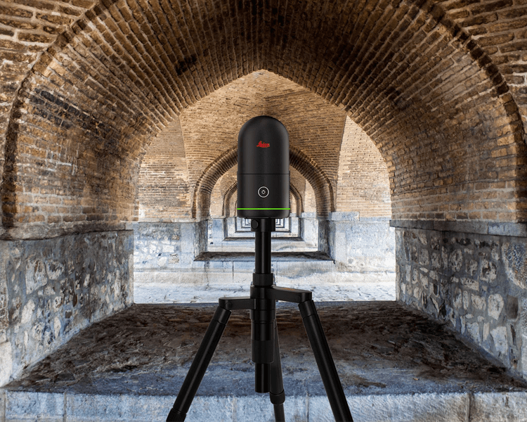 Laser scanner on tripod in arched corridor.