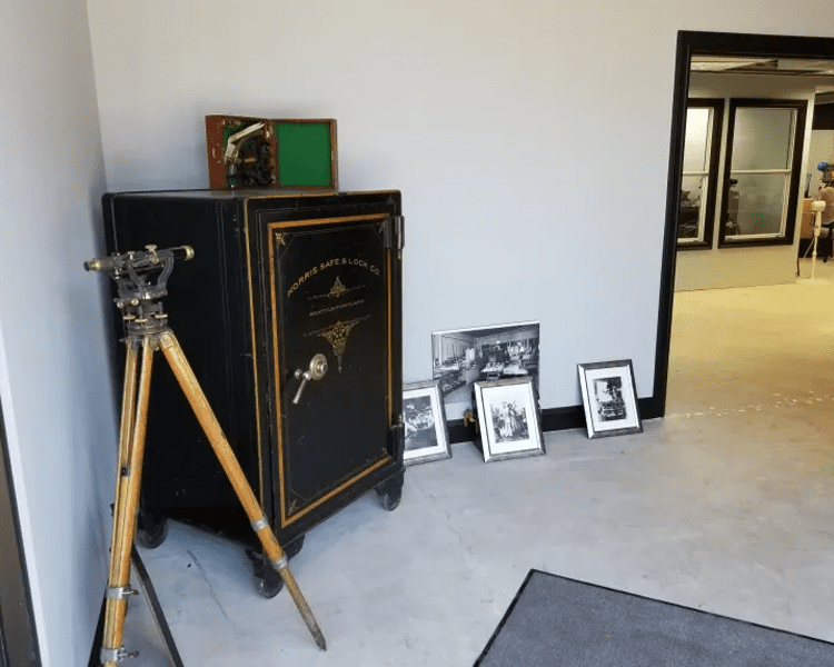 Old safe and wooden tripod in room.