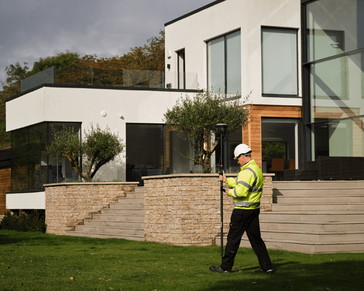 Worker measuring near modern home exterior.