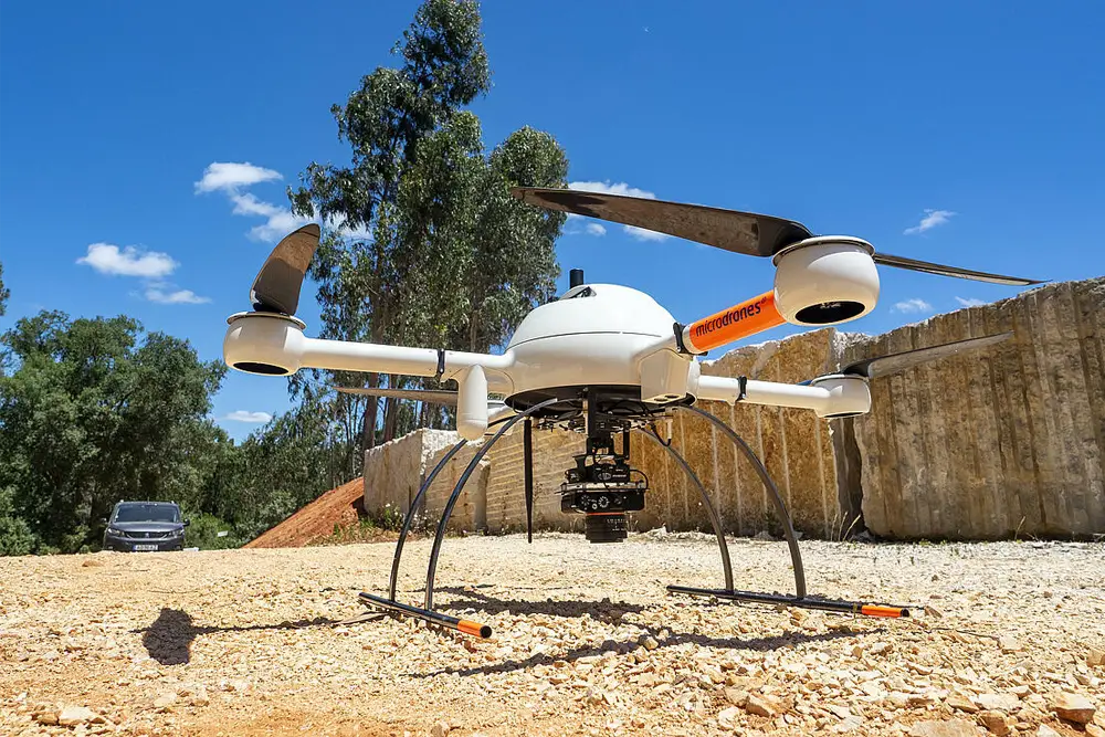 White Microdrones drone on gravel ground.