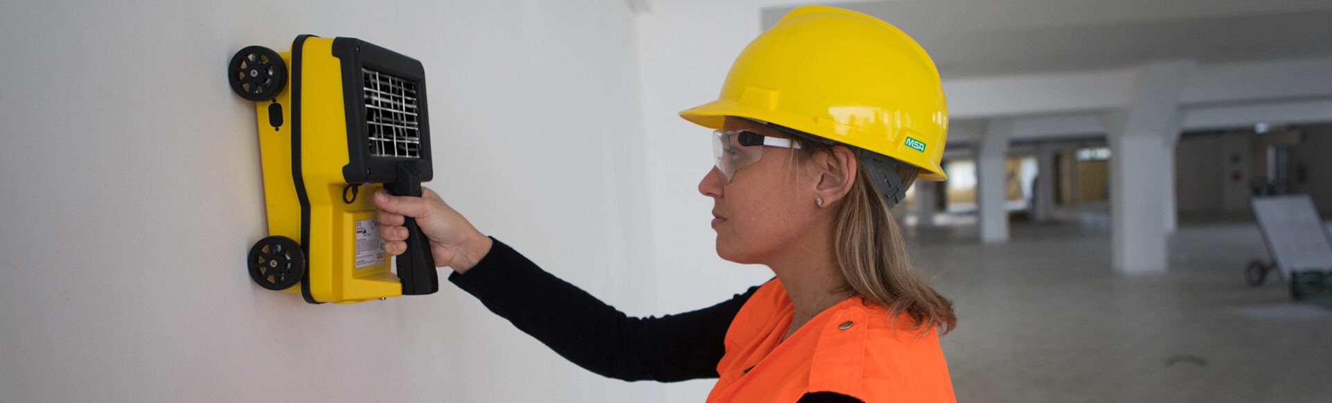 Woman using a device on a wall.